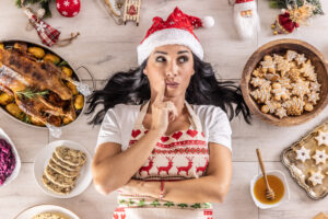 Mujer reflexionando ante distintos platos típicos navideños, representando las dudas habituales sobre cómo gestionar la alimentación durante las fiestas.