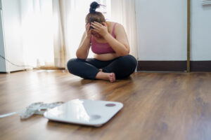 Mujer frustrada frente a una báscula tras no lograr adelgazar pese a hacer dieta